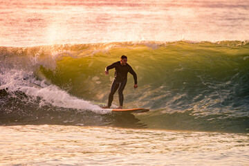 Wall Mural - Young Man Riding Wave at Sunset