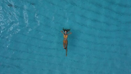 Wall Mural - Woman relaxing and swims in blue ocean at tropical island. Aerial view.