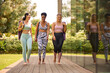 Three Mature Female Friends Outdoors In Fitness Clothing Carrying Exercise Mats At Gym Or Yoga Class