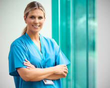 Portrait Of Mature Smiling Female Doctor Wearing Scrubs In Hospital