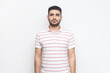 © khosrork - Portrait of strict serious bossy bearded man wearing striped t-shirt standing looking at camera, having assertive facial expression. Indoor studio shot isolated on gray background.