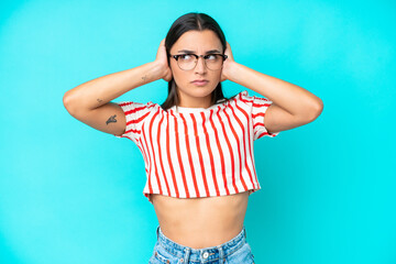 Wall Mural - Young caucasian woman isolated on blue background frustrated and covering ears