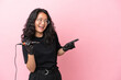 Tattoo artist asian woman isolated on pink background pointing finger to the side and presenting a product