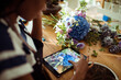 © Davor - Young woman florist taking picture of bouquet in flower store