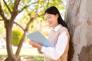 Wall Mural - Pretty Chinese woman at outdoors holding a notebook