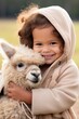 © olegganko - A beaming toddler cradles a fluffy and contented baby alpaca,