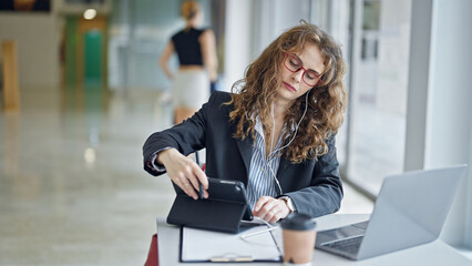 Canvas Print - Young woman business worker using touchpad and earphones working at the office