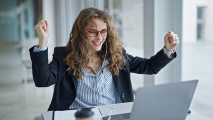 Poster - Young woman business worker using laptop and earphones with winner gesture at the office