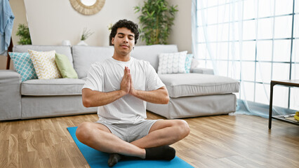 Sticker - Young latin man sitting on floor training yoga at home