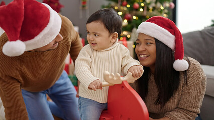 Poster - Couple and son playing with reindeer rocking by christmas tree at home