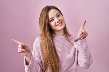 Canvas Print - Young caucasian woman standing over pink background smiling confident pointing with fingers to different directions. copy space for advertisement