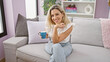© Krakenimages.com - Young blonde woman drinking coffee sitting on sofa at home