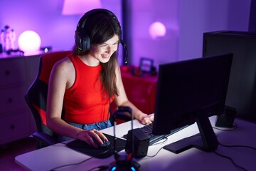 Wall Mural - Young caucasian woman streamer playing video game using computer at gaming room