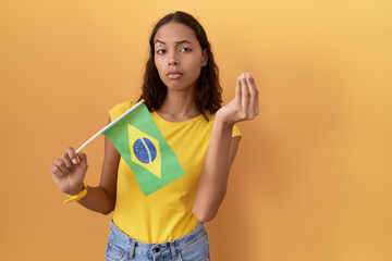 Poster - Young hispanic woman holding brazil flag doing italian gesture with hand and fingers confident expression