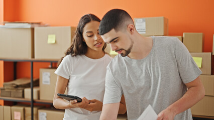 Wall Mural - Together in business, two serious workers, a man and woman, concentrate on reading a document on a laptop at the office