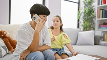 Sticker - Mother and daughter bond over drawing on the sofa; mom balancing cellphone conversation and family time at home