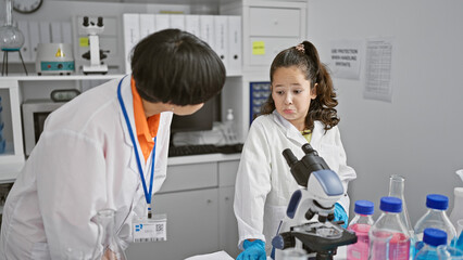 Wall Mural - Two serious-faced scientist partners standing together, speaking about medical research analysis in lab