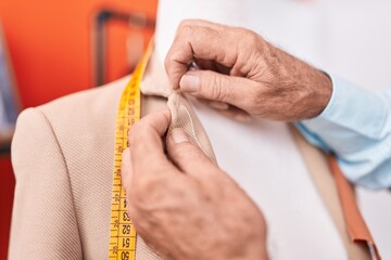 Canvas Print - Middle age grey-haired man tailor sewing jacket on manikin at atelier