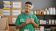 © Krakenimages.com - Young, confident latin volunteer man, hands on heart, smiling while standing in charity center - a portrait of supportive altruism