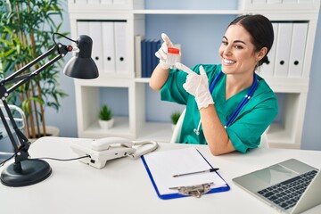 Canvas Print - Young beautiful hispanic woman doctor holding test tube sitting on table at clinic