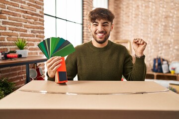 Sticker - Arab man with beard moving to a new home choosing walls paint screaming proud, celebrating victory and success very excited with raised arm