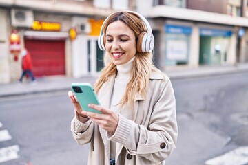 Poster - Young blonde woman listening to music at street