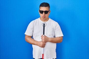 Canvas Print - Hispanic young blind man holding cane depressed and worry for distress, crying angry and afraid. sad expression.