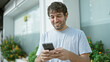 © Krakenimages.com - Happy young man, sporting a beard and blond hair, enjoying his time outdoor in the city, confidently smiling while typing a message on his smartphone screen