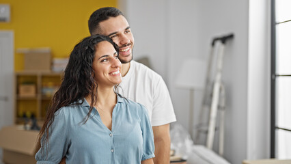 Wall Mural - Man and woman couple standing together looking throw the window at new home