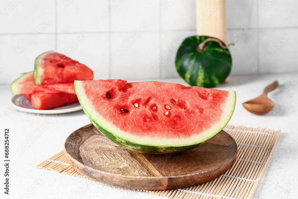 Wooden board with piece of fresh watermelon on white table