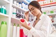 © Krakenimages.com - Young beautiful hispanic woman customer reading medication label bottle at pharmacy
