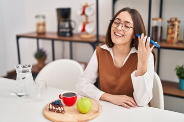 Poster - Young beautiful hispanic woman having breakfast listening voice message by smartphone at home
