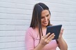 © Krakenimages.com - Young beautiful hispanic woman smiling confident using touchpad over isolated white brick background