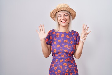 Poster - Young caucasian woman wearing flowers dress and summer hat showing and pointing up with fingers number nine while smiling confident and happy.