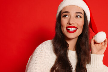 Sticker - Christmas celebration. Beautiful young woman in Santa hat on red background, space for text