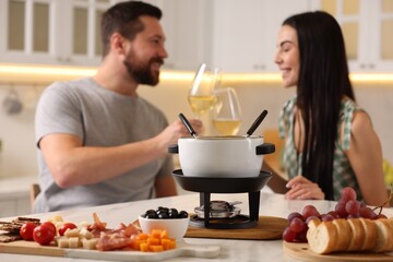 Wall Mural - Couple spending time together during romantic date in kitchen, focus on fondue