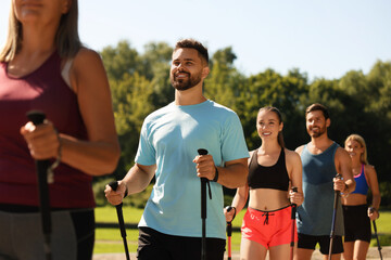 Poster - Group of people practicing Nordic walking with poles outdoors on sunny day