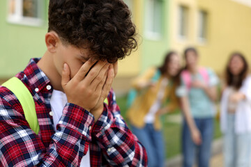 Teen problems. Group of students pointing at upset boy outdoors, selective focus