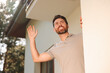 Neighbor greeting. Happy man waving near house outdoors, low angle view