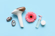 Modern photoepilator with gerbera flower, attachments and cosmetic products on blue background