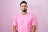 Fototapeta  - Hispanic young man standing over pink background puffing cheeks with funny face. mouth inflated with air, crazy expression.