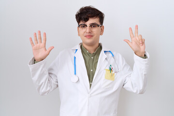 Canvas Print - Young non binary man wearing doctor uniform and stethoscope showing and pointing up with fingers number eight while smiling confident and happy.