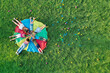 © New Africa - Group of children with teachers holding hands together on rainbow playground parachute in park, top view. Summer camp activity
