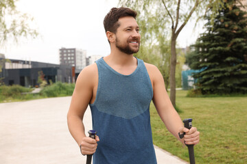 Wall Mural - Man practicing Nordic walking with poles outdoors