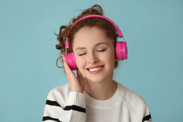 Wall Mural - Portrait of relaxed young woman listening to music on blue background