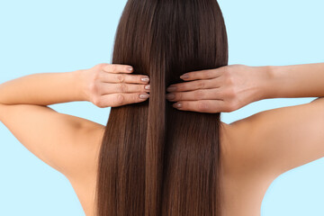 Wall Mural - Young brunette woman with beautiful hair on blue background, back view