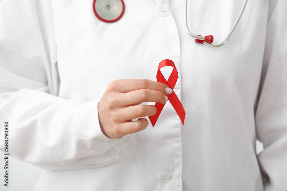 Young female doctor with red ribbon, closeup. World AIDS day concept