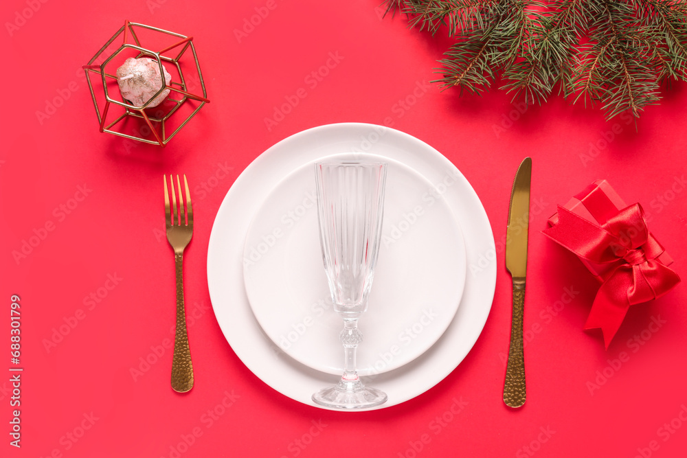 Beautiful table setting with Christmas tree branches, gift box and candle on red background