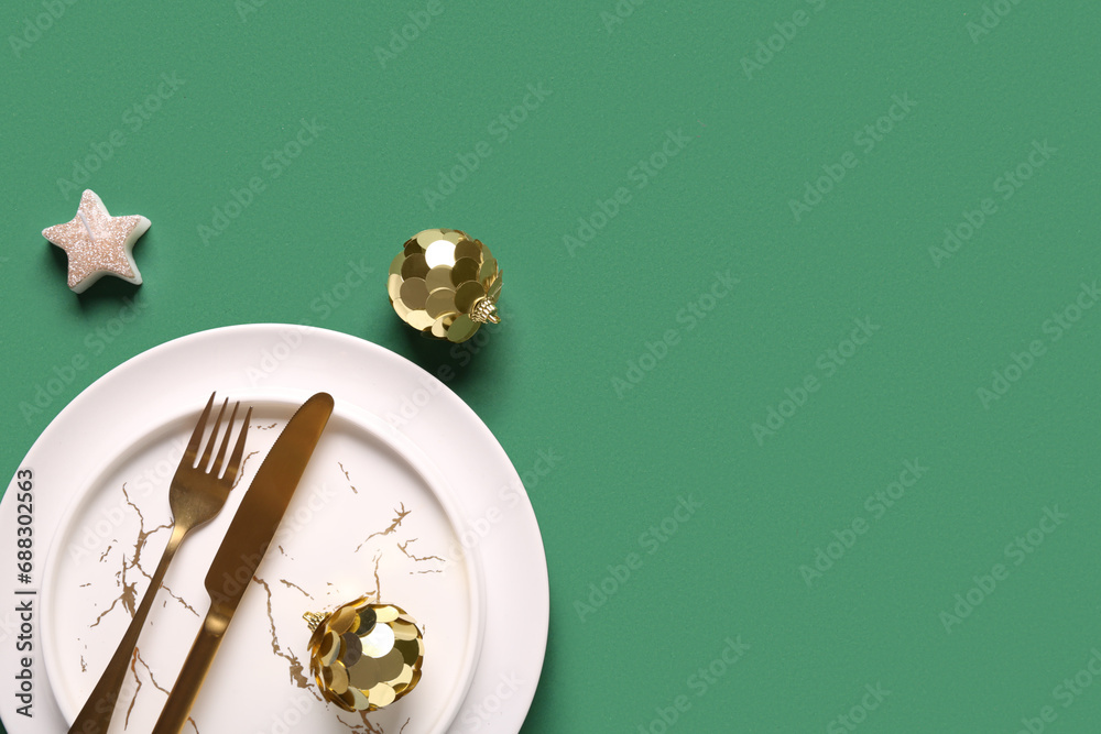 Beautiful table setting with Christmas balls and candle on green background