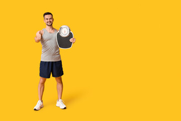 Sticker - Handsome sporty young man with scales showing thumb-up gesture on yellow background. Weight loss concept